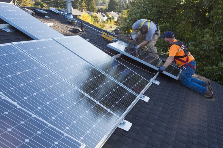Certified installers fitting solar panels on a domestic roof
